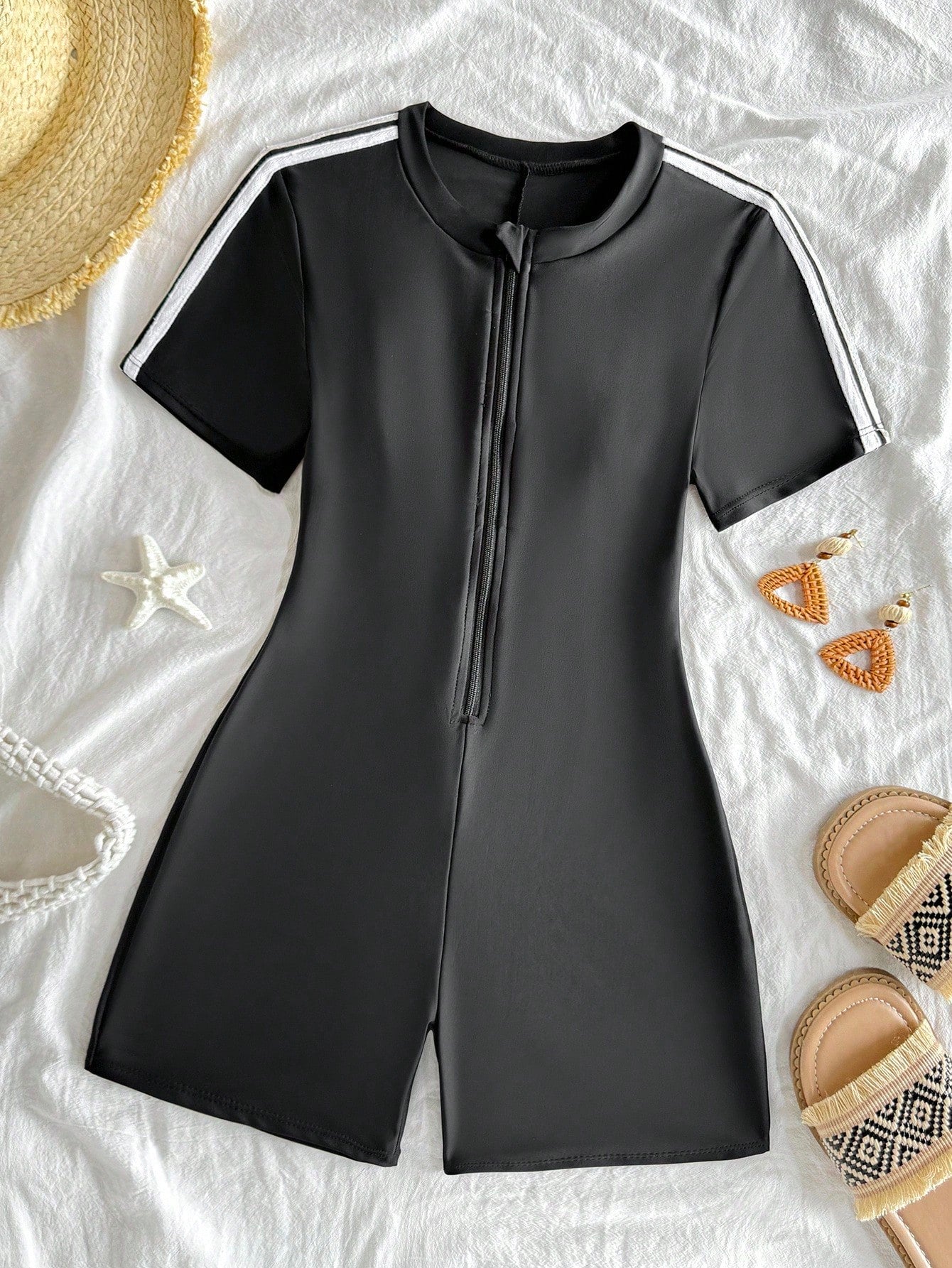 Black and white one-piece rashguard swimsuit for tween girls with short sleeves, high neck, zipper detail, fitted shape, and shorts-style bottom.