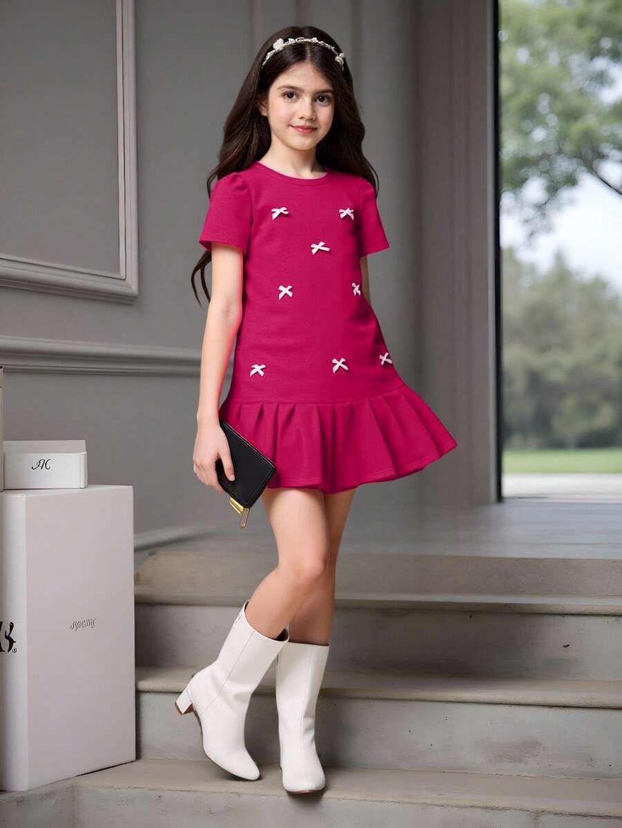 Tween girls apricot short-sleeve pleated smock dress with 3D bow decor and round neckline.