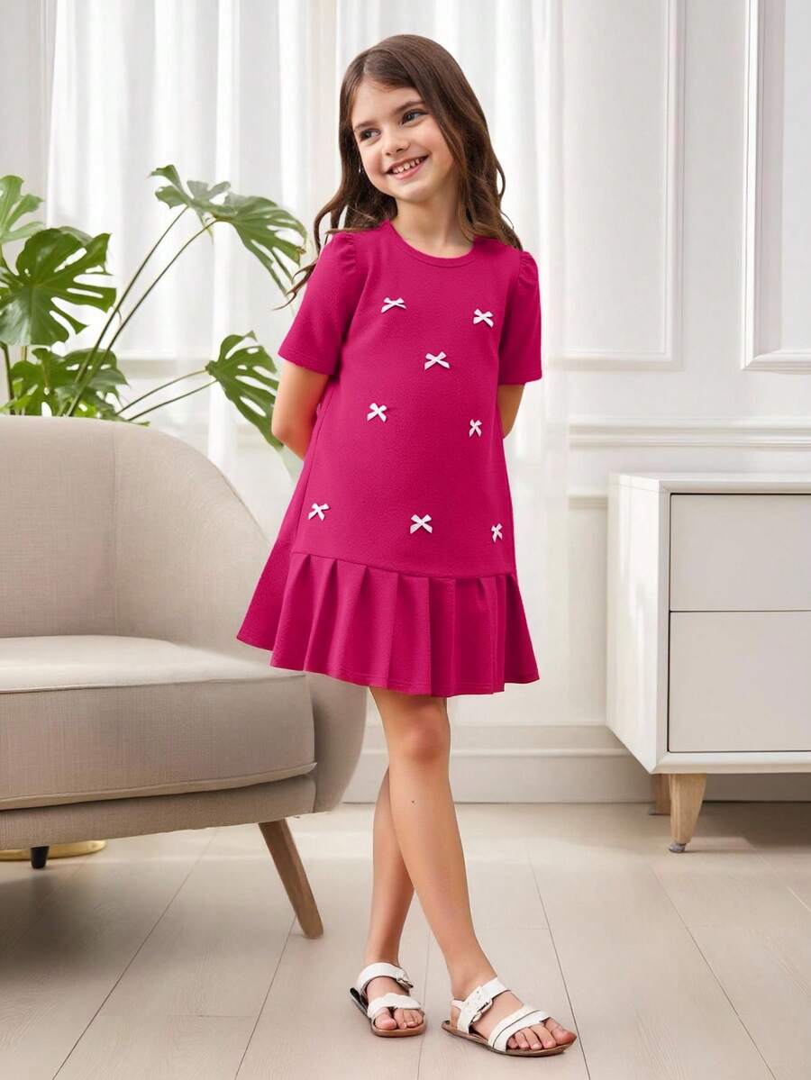 Tween girls apricot short-sleeve pleated smock dress with 3D bow decor and round neckline.