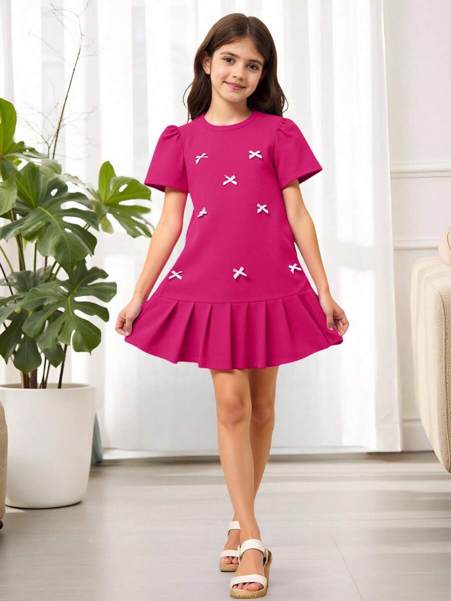 Tween girls apricot short-sleeve pleated smock dress with 3D bow decor and round neckline.