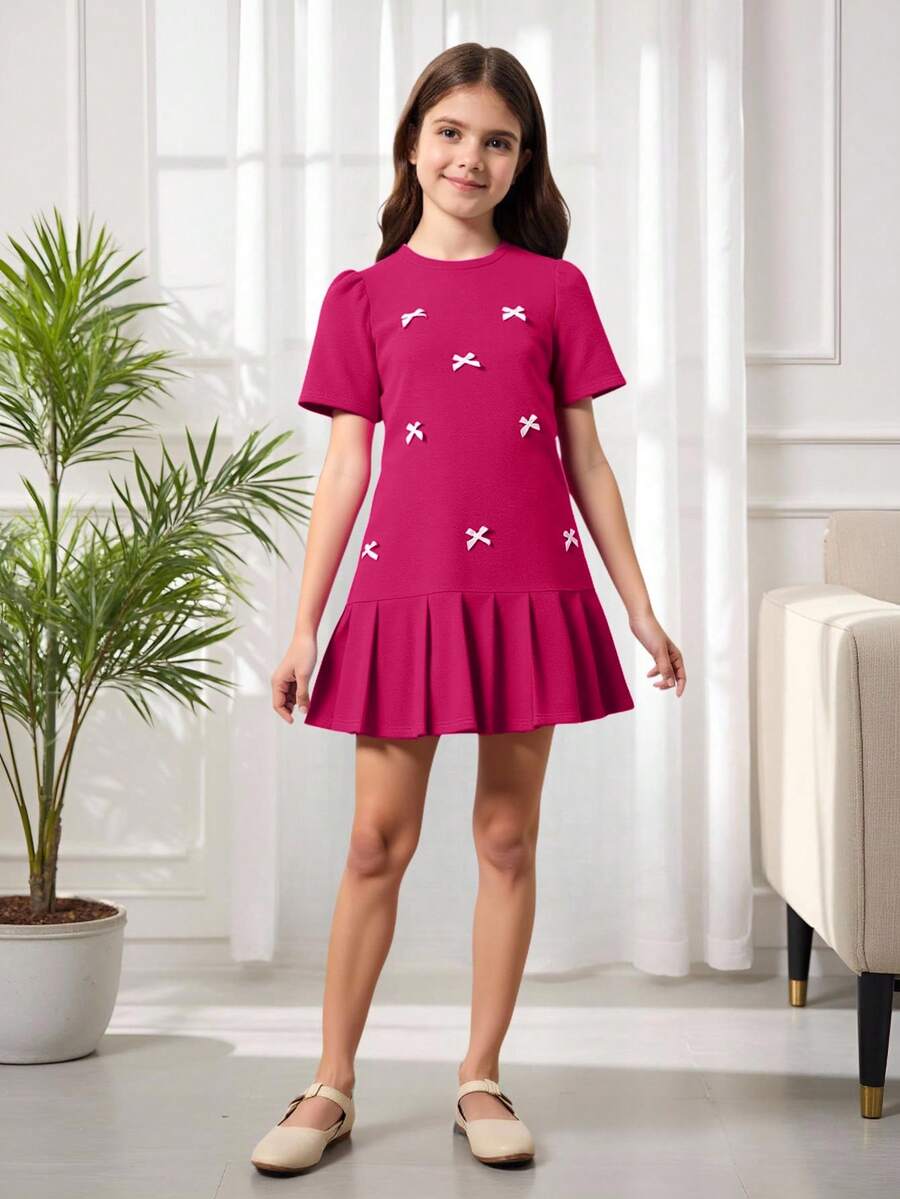 Tween girls apricot short-sleeve pleated smock dress with 3D bow decor and round neckline.