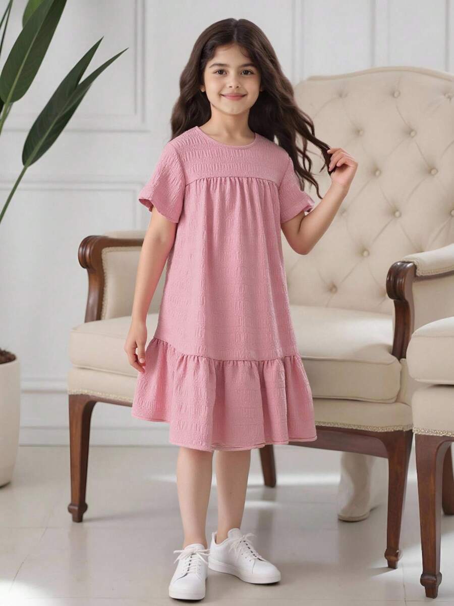 Tween girl wearing an Army Green textured short sleeve smock midi dress with round neck and ruffle flounce hem.