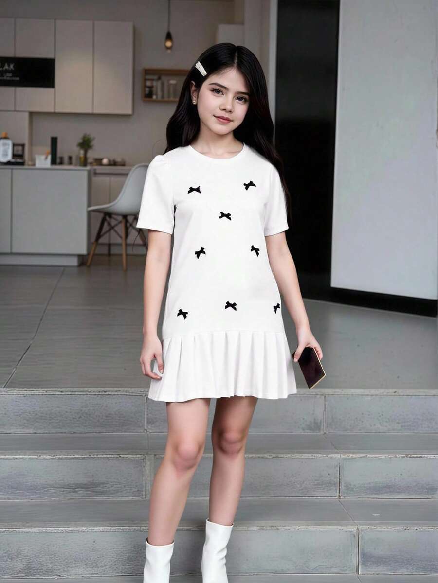Tween girls apricot short-sleeve pleated smock dress with 3D bow decor and round neckline.