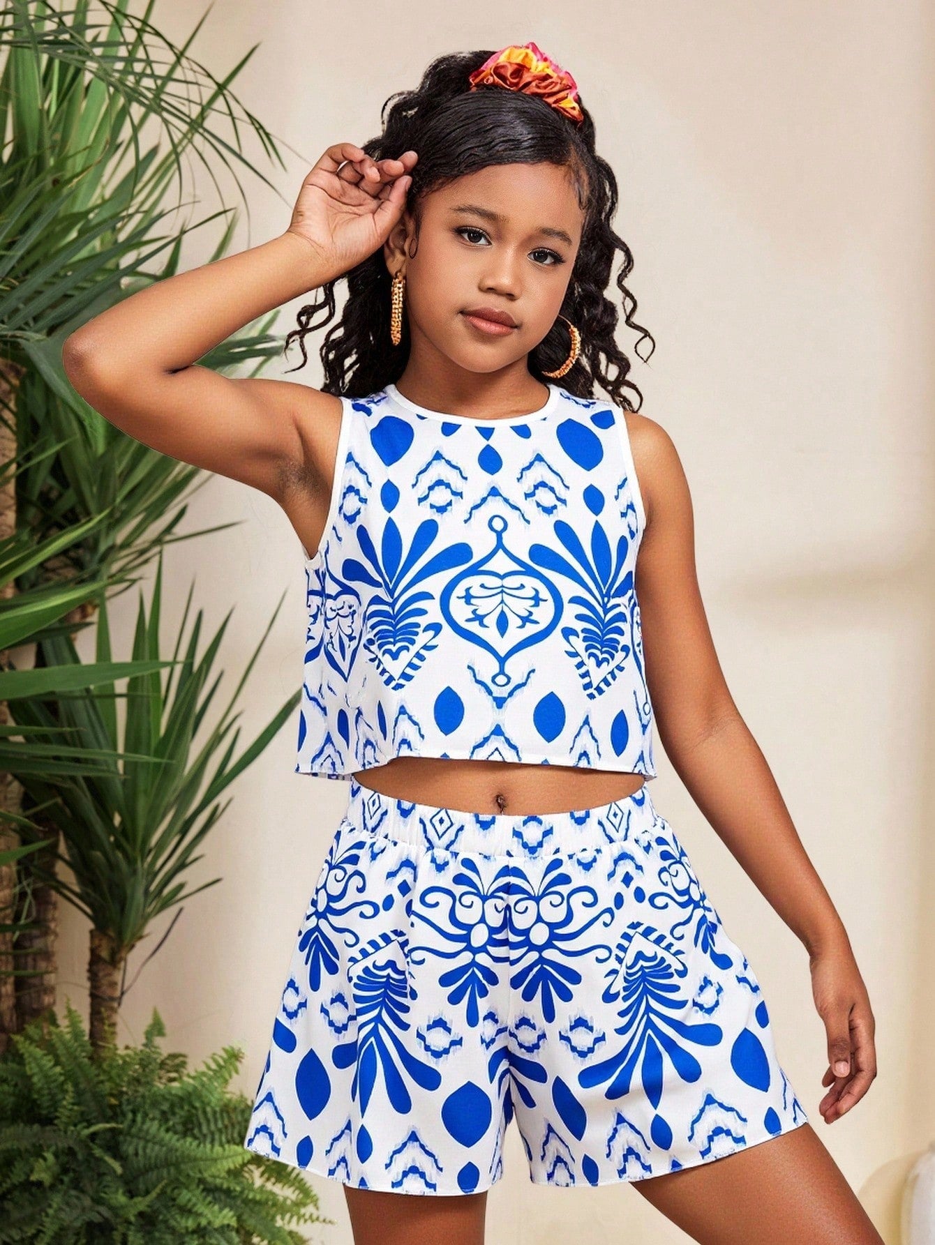 Tween girl wearing a tropical floral print two-piece vacation set featuring a sleeveless round neck tank top with button details and matching shorts.