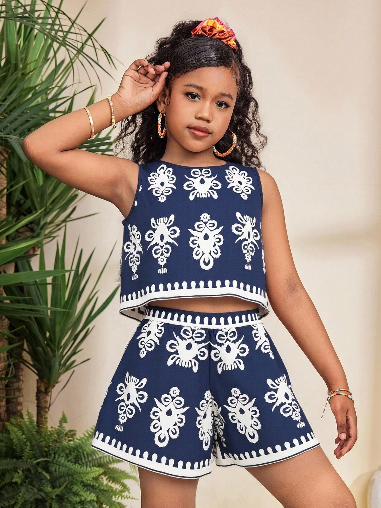 Tween girl wearing a tropical floral print two-piece vacation set featuring a sleeveless round neck tank top with button details and matching shorts.