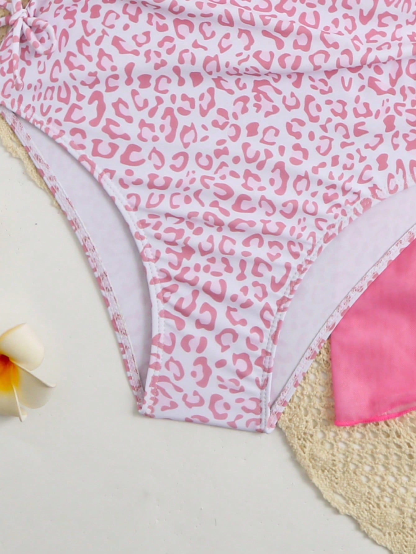 Tween girls 2-piece swimsuit in black with pink floral print, featuring spaghetti straps, bow decor, mesh detail, and a skirted mid-waist bottom. Sleeveless vacation-style swim set with medium-stretch fabric.