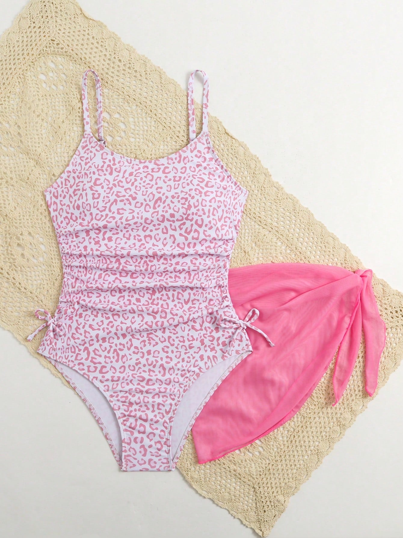 Tween girls 2-piece swimsuit in black with pink floral print, featuring spaghetti straps, bow decor, mesh detail, and a skirted mid-waist bottom. Sleeveless vacation-style swim set with medium-stretch fabric.