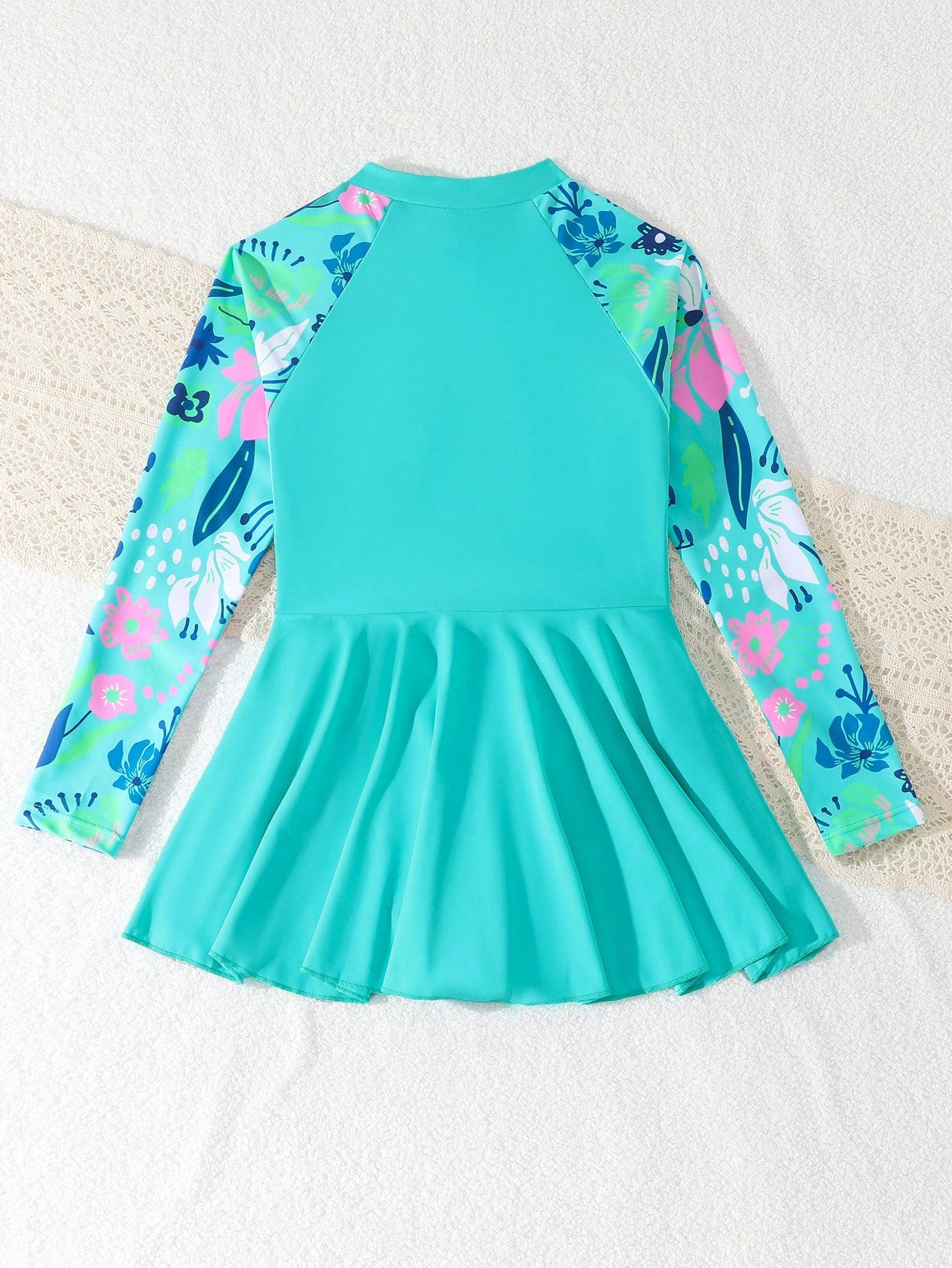 Tween girls one-piece swimsuit in black floral pattern with long sleeves, high neck, front zipper, and a skirt-style bottom.