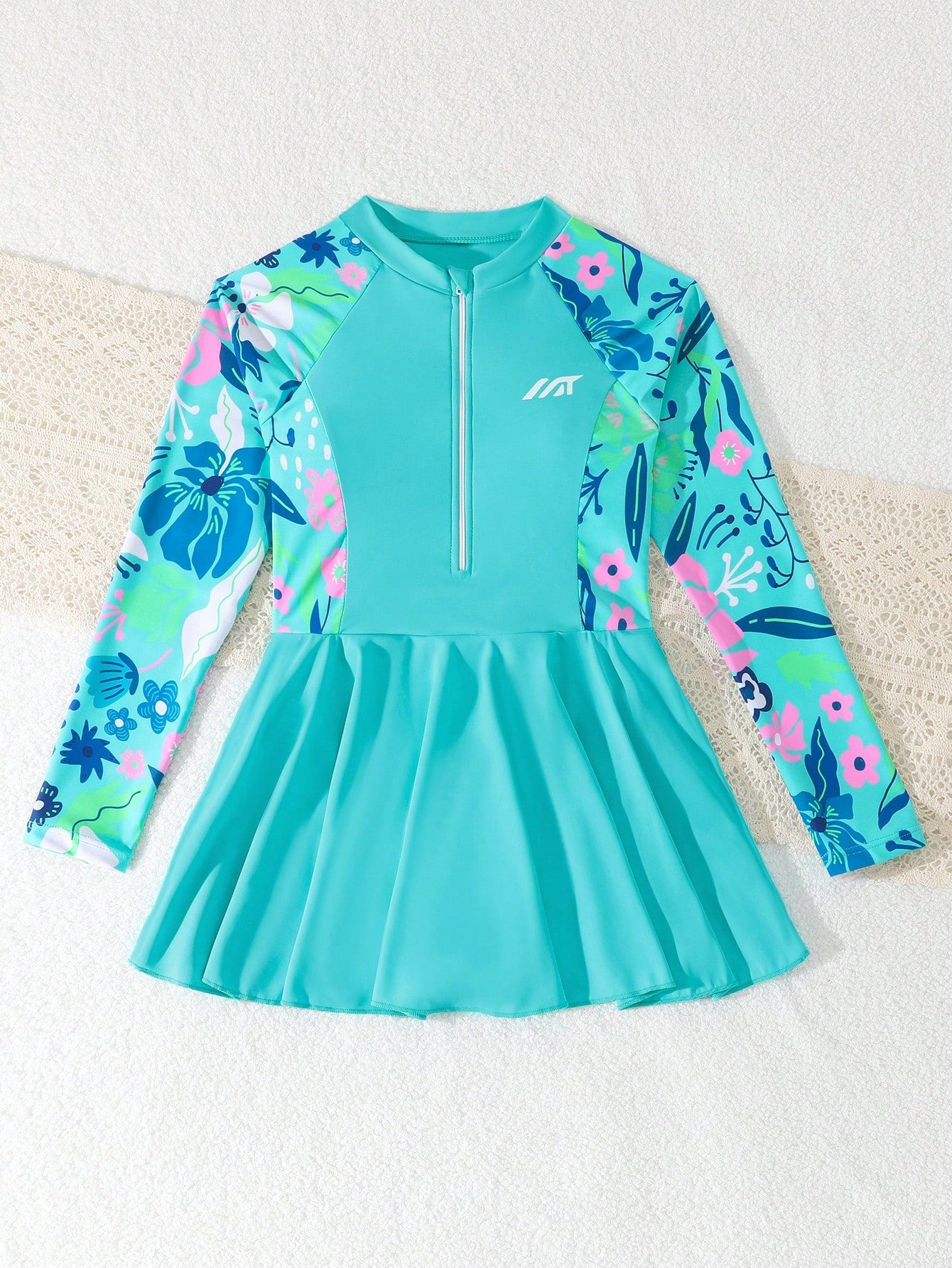 Tween girls one-piece swimsuit in black floral pattern with long sleeves, high neck, front zipper, and a skirt-style bottom.