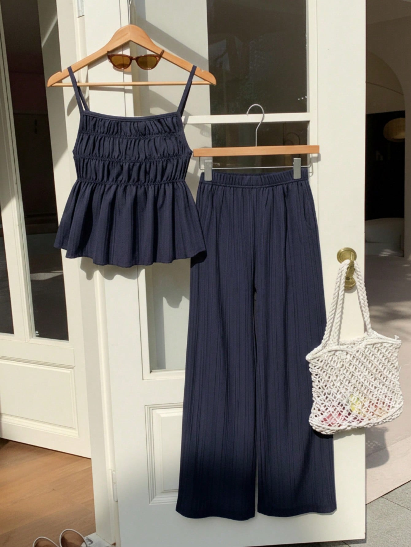 Tween girl wearing an apricot 2-piece outfit set featuring a shirred spaghetti strap short cami top and matching wide-leg long pants.