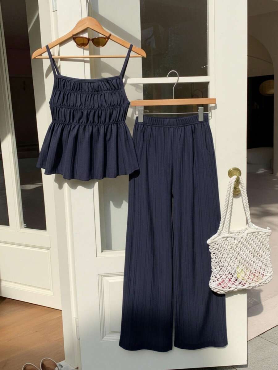 Tween girl wearing an apricot 2-piece outfit set featuring a shirred spaghetti strap short cami top and matching wide-leg long pants.
