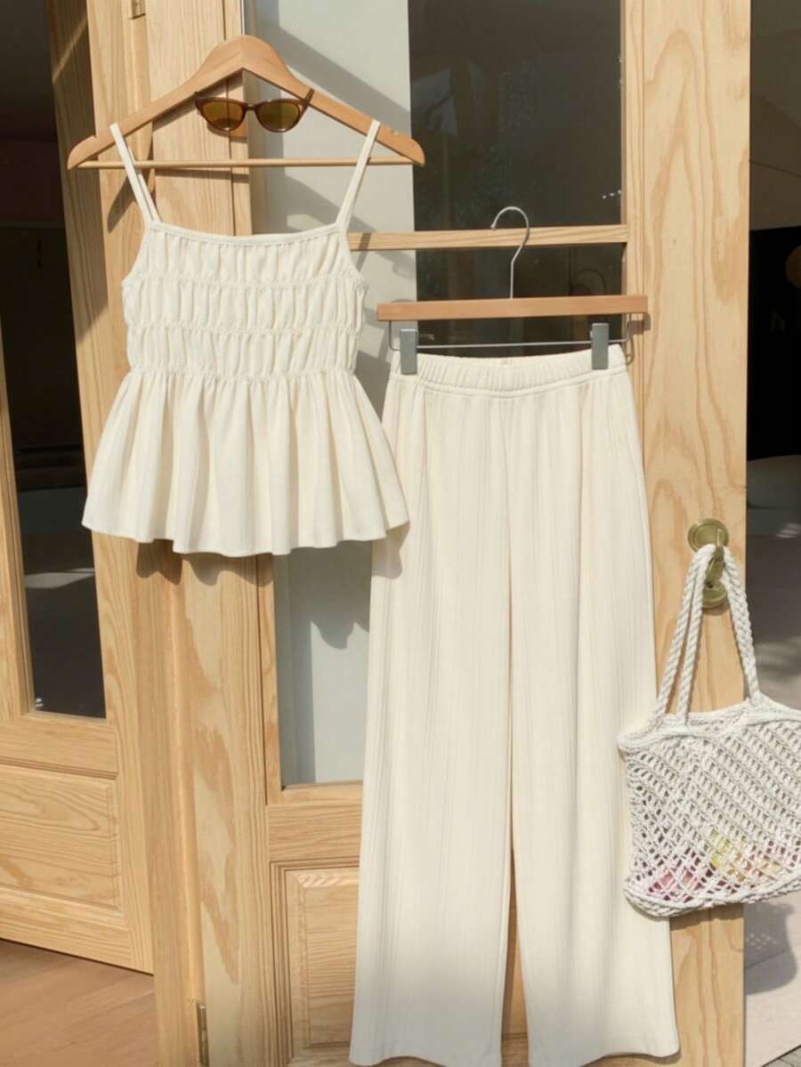 Tween girl wearing an apricot 2-piece outfit set featuring a shirred spaghetti strap short cami top and matching wide-leg long pants.
