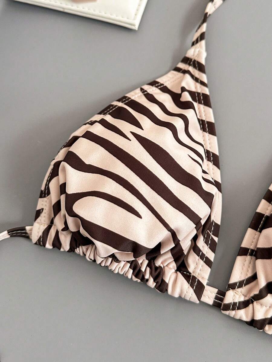 Women's black and white zebra print two-piece bikini set featuring a high waist tie-side bottom and a backless halter top with removable padding.
