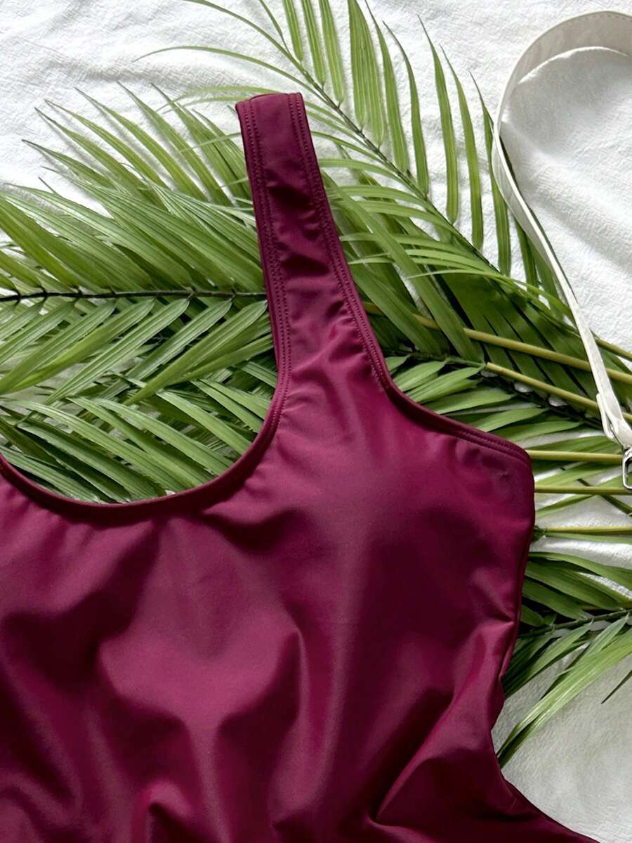 Women's solid color one-piece swimsuit featuring a backless scoop neck design and high cut fit
