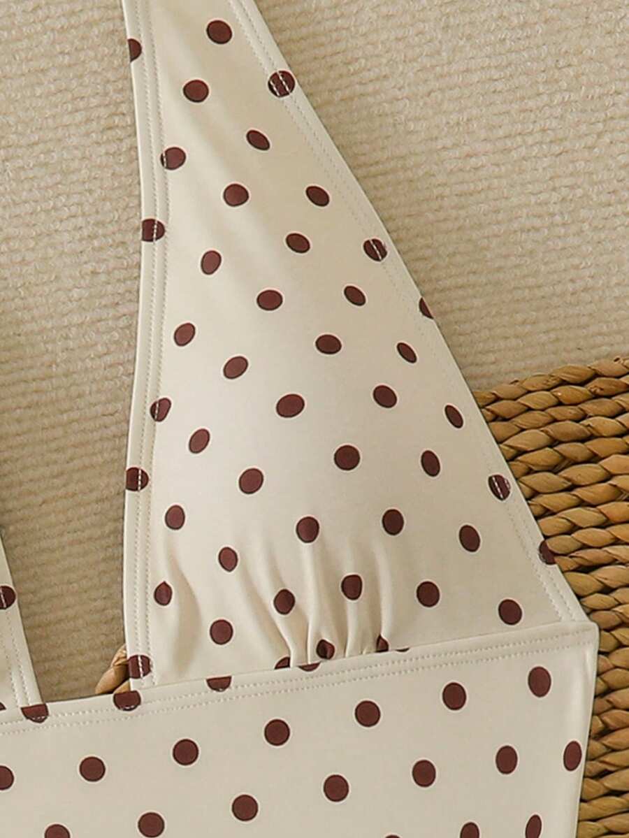 Women's apricot polka dot two-piece swimsuit featuring an asymmetrical halter backless top with knot tie detail and high-waisted bottoms.