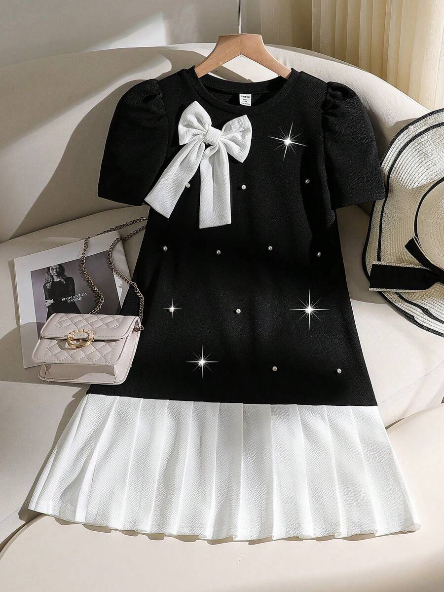 Tween girls apricot short-sleeve pleated smock dress with 3D bow decor and round neckline.