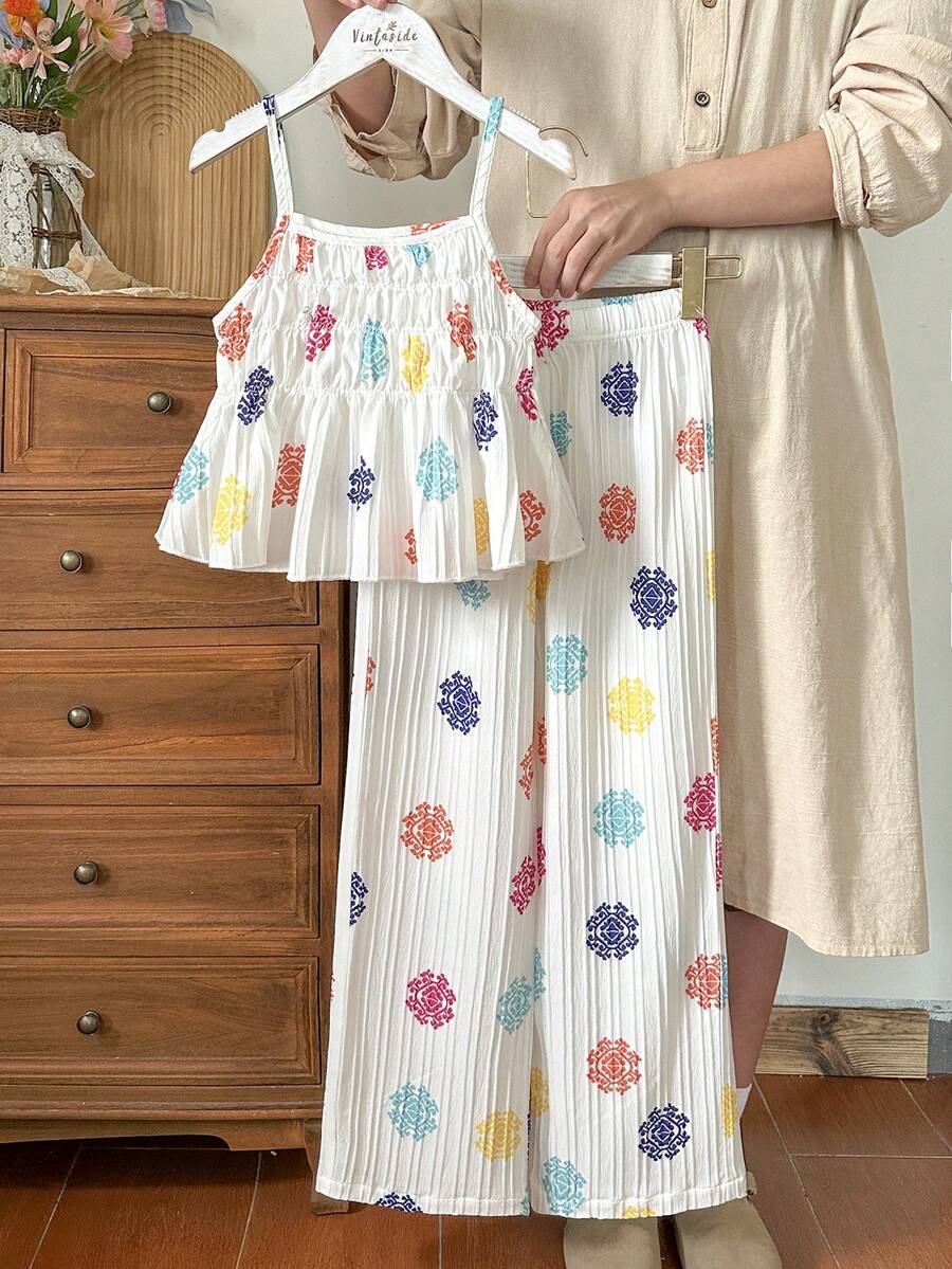 Tween girl wearing an apricot 2-piece outfit set featuring a shirred spaghetti strap short cami top and matching wide-leg long pants.