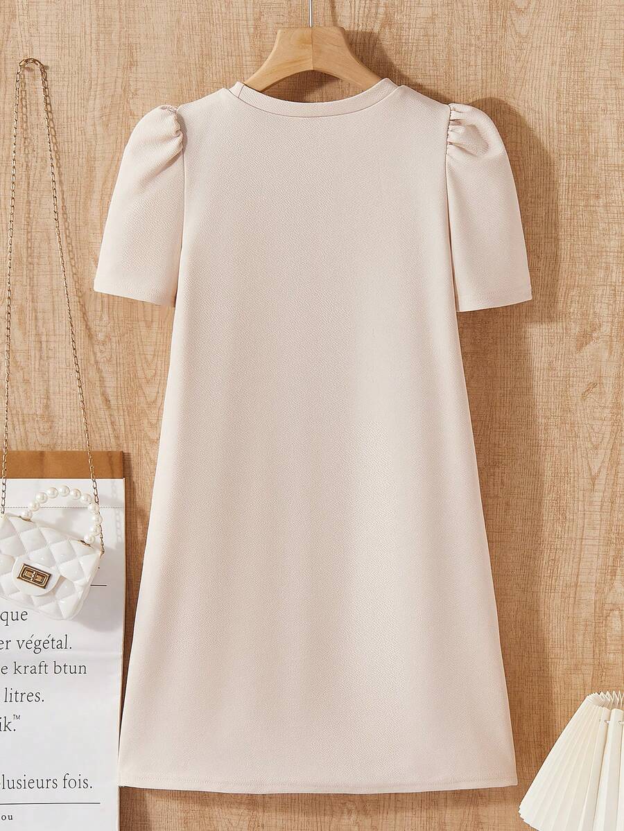 Tween girls apricot short-sleeve pleated smock dress with 3D bow decor and round neckline.