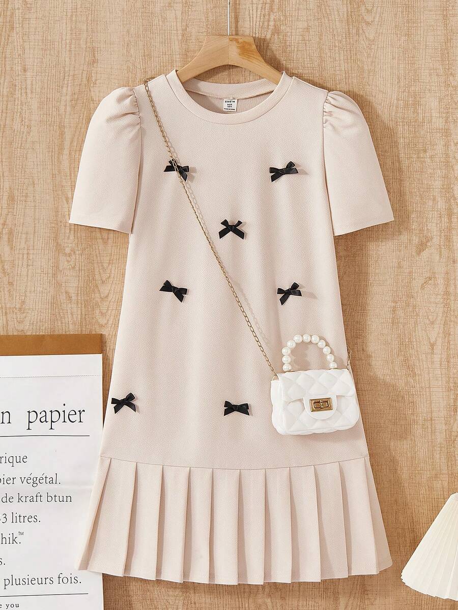 Tween girls apricot short-sleeve pleated smock dress with 3D bow decor and round neckline.