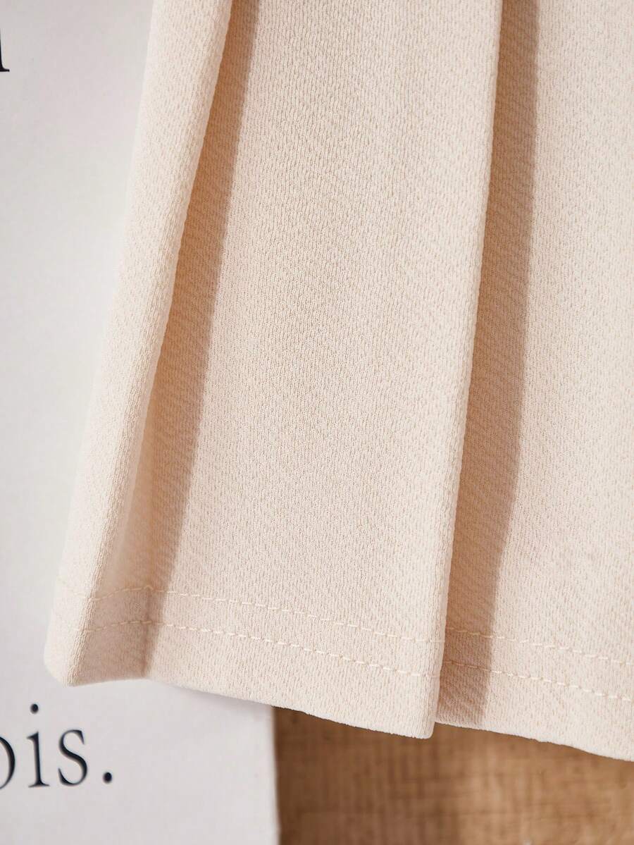 Tween girls apricot short-sleeve pleated smock dress with 3D bow decor and round neckline.