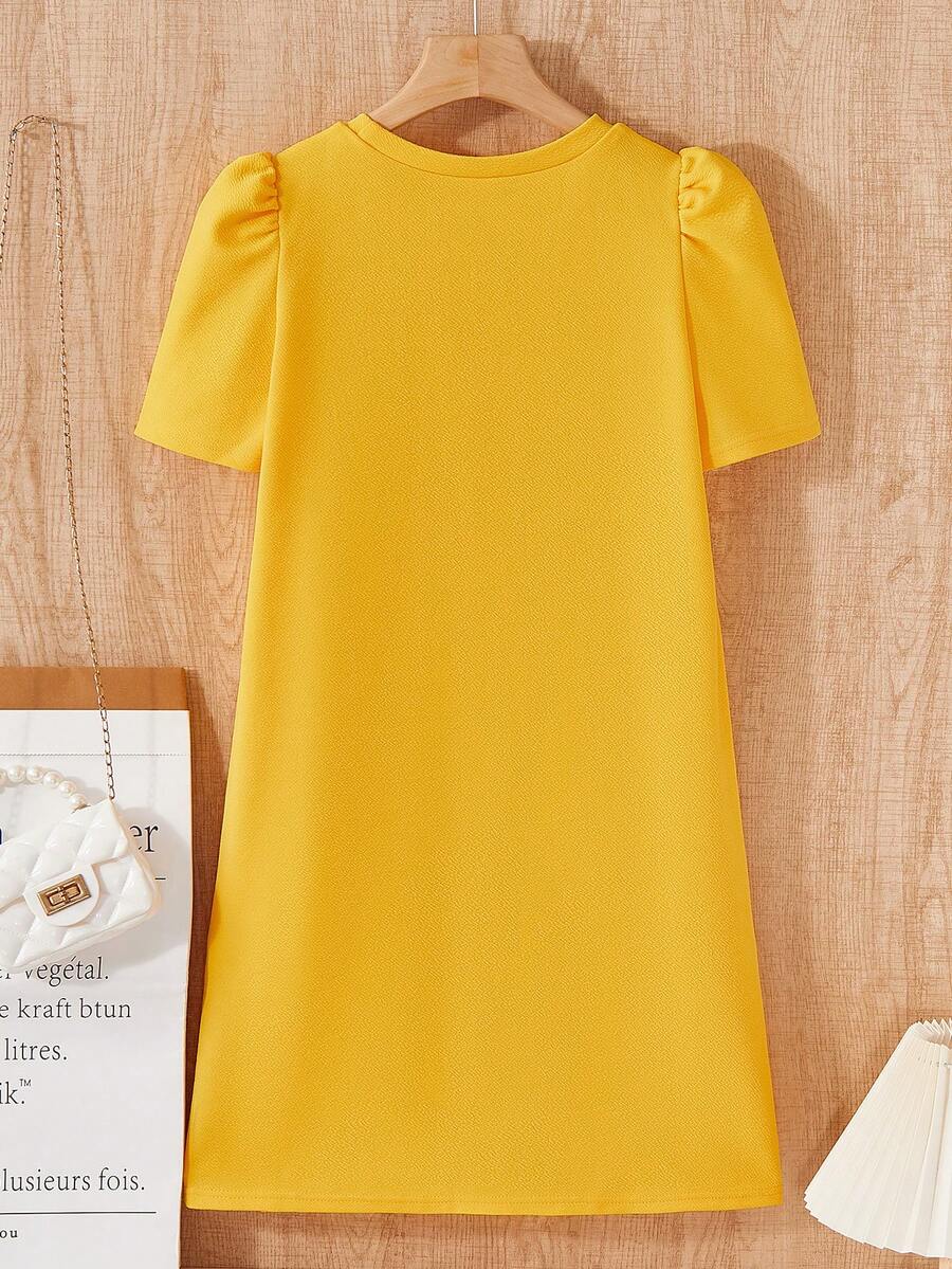 Tween girls apricot short-sleeve pleated smock dress with 3D bow decor and round neckline.