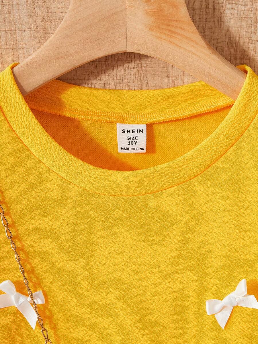 Tween girls apricot short-sleeve pleated smock dress with 3D bow decor and round neckline.