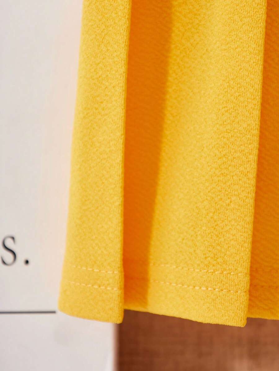 Tween girls apricot short-sleeve pleated smock dress with 3D bow decor and round neckline.