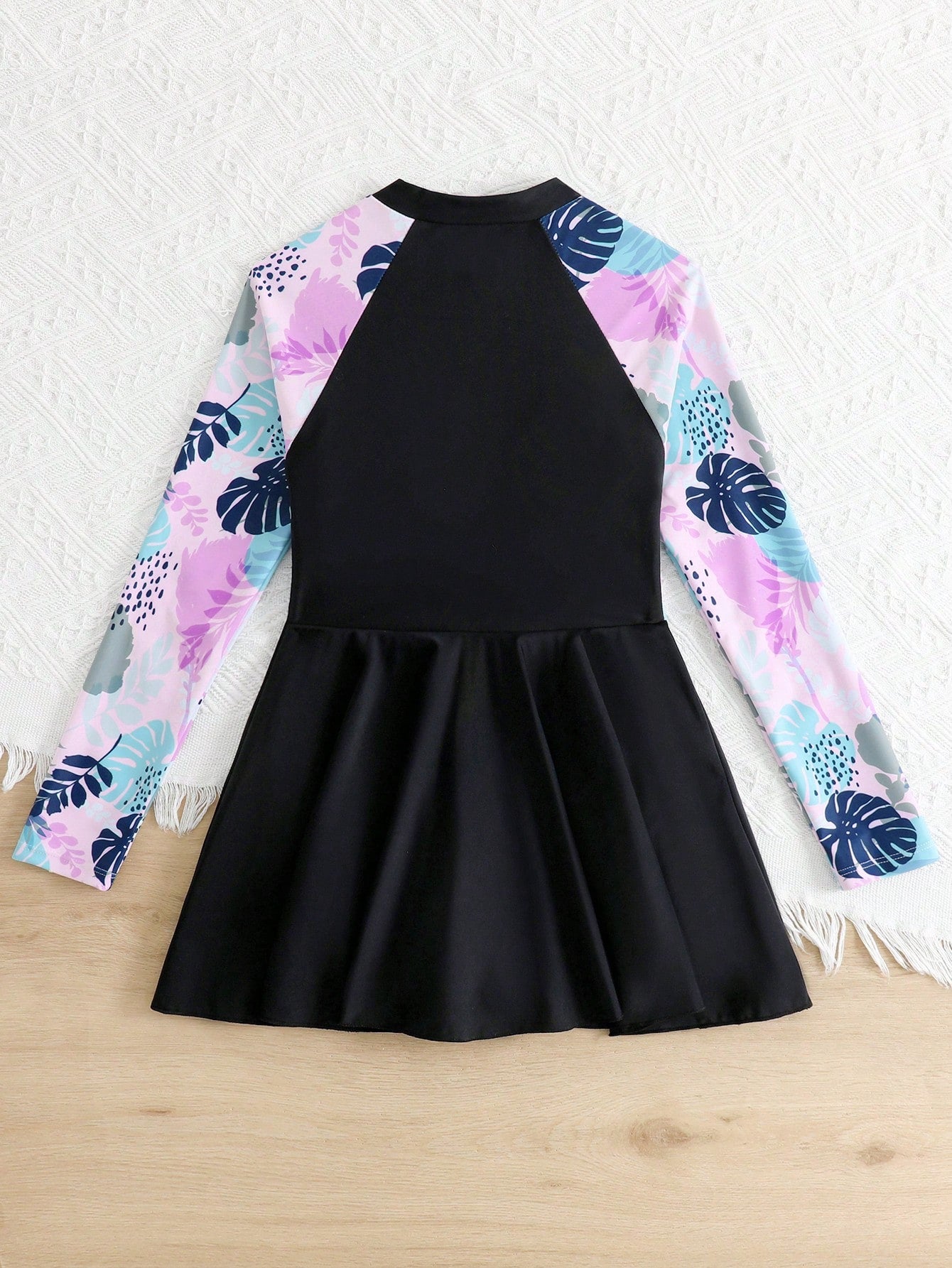 Tween girls one-piece swimsuit in black floral pattern with long sleeves, high neck, front zipper, and a skirt-style bottom.