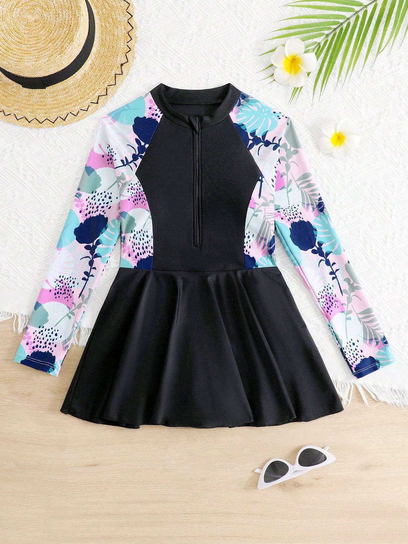 Tween girls one-piece swimsuit in black floral pattern with long sleeves, high neck, front zipper, and a skirt-style bottom.