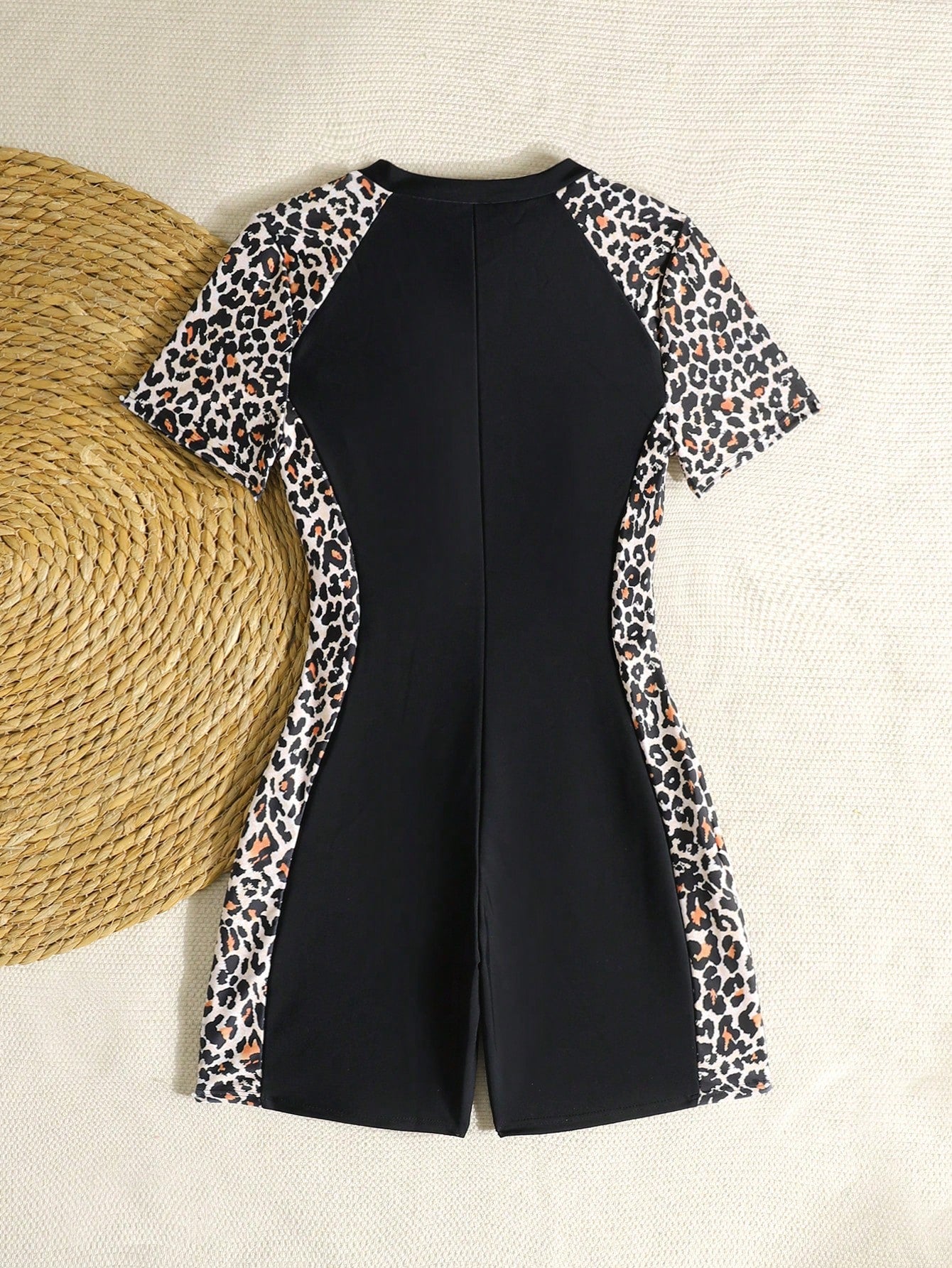 Black and white one-piece rashguard swimsuit for tween girls with short sleeves, high neck, zipper detail, fitted shape, and shorts-style bottom.