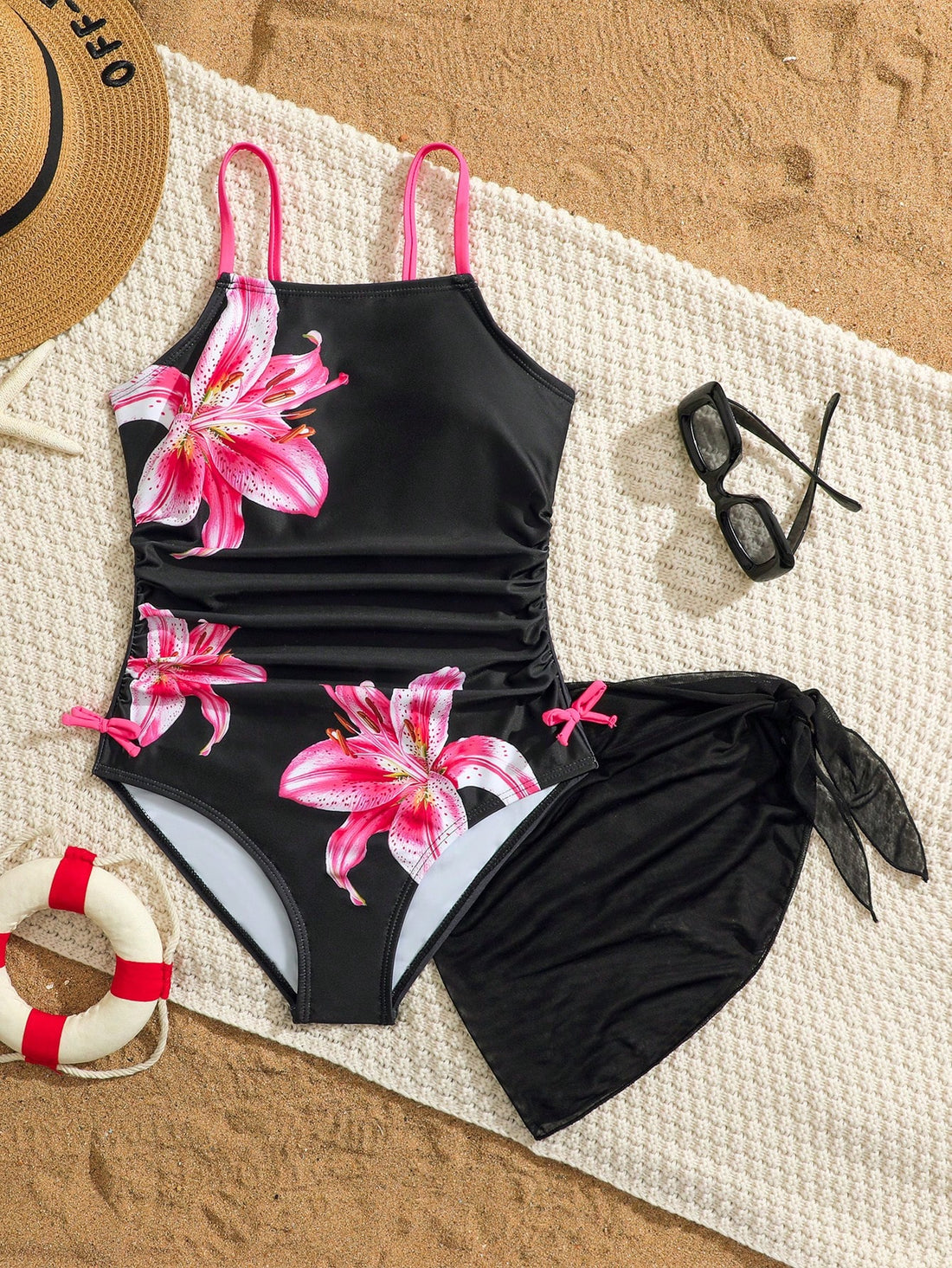 Tween girls 2-piece swimsuit in black with pink floral print, featuring spaghetti straps, bow decor, mesh detail, and a skirted mid-waist bottom. Sleeveless vacation-style swim set with medium-stretch fabric.