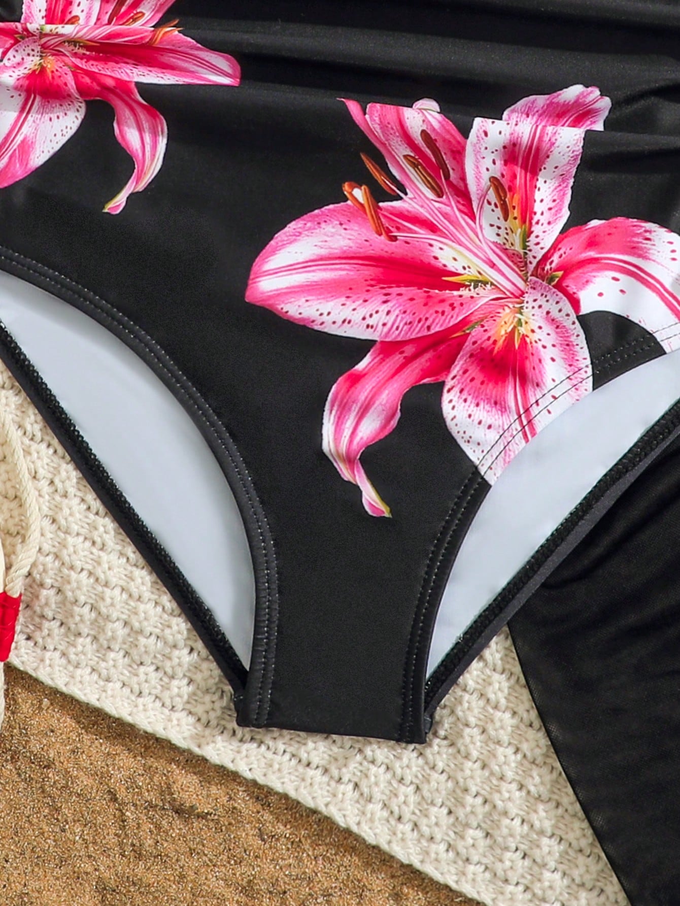 Tween girls 2-piece swimsuit in black with pink floral print, featuring spaghetti straps, bow decor, mesh detail, and a skirted mid-waist bottom. Sleeveless vacation-style swim set with medium-stretch fabric.