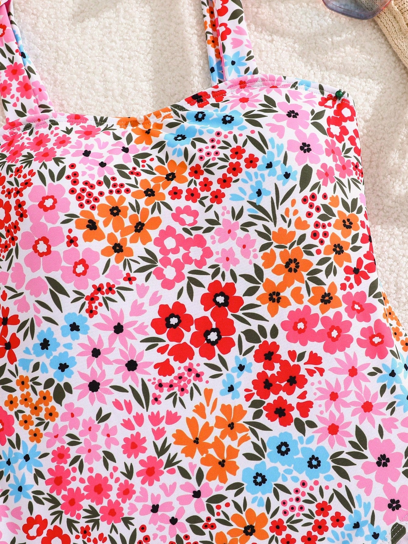 Tween girl floral print one-piece swimsuit with twist front, spaghetti straps, fitted shape, and multicolor all-over hibiscus-inspired pattern for beach and pool wear.