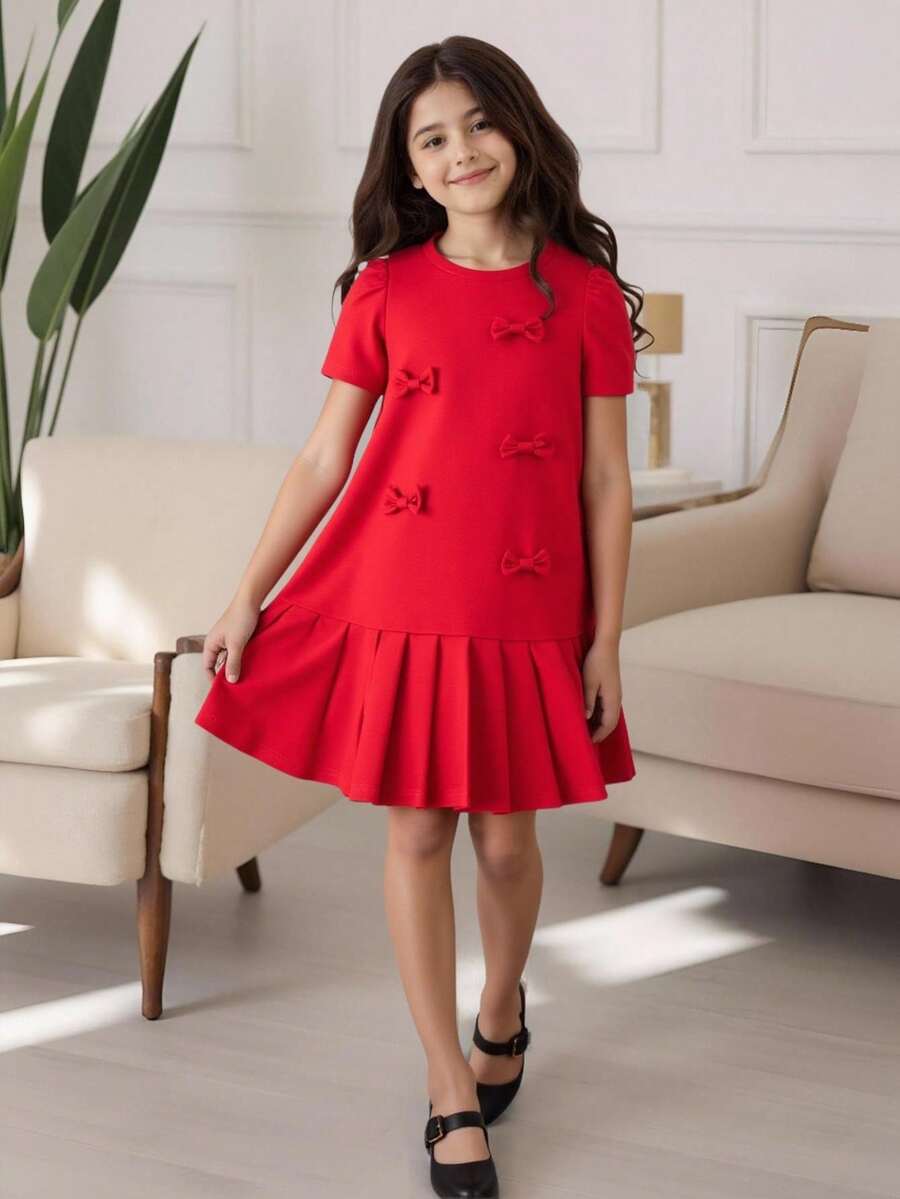 Tween girls apricot short-sleeve pleated smock dress with 3D bow decor and round neckline.