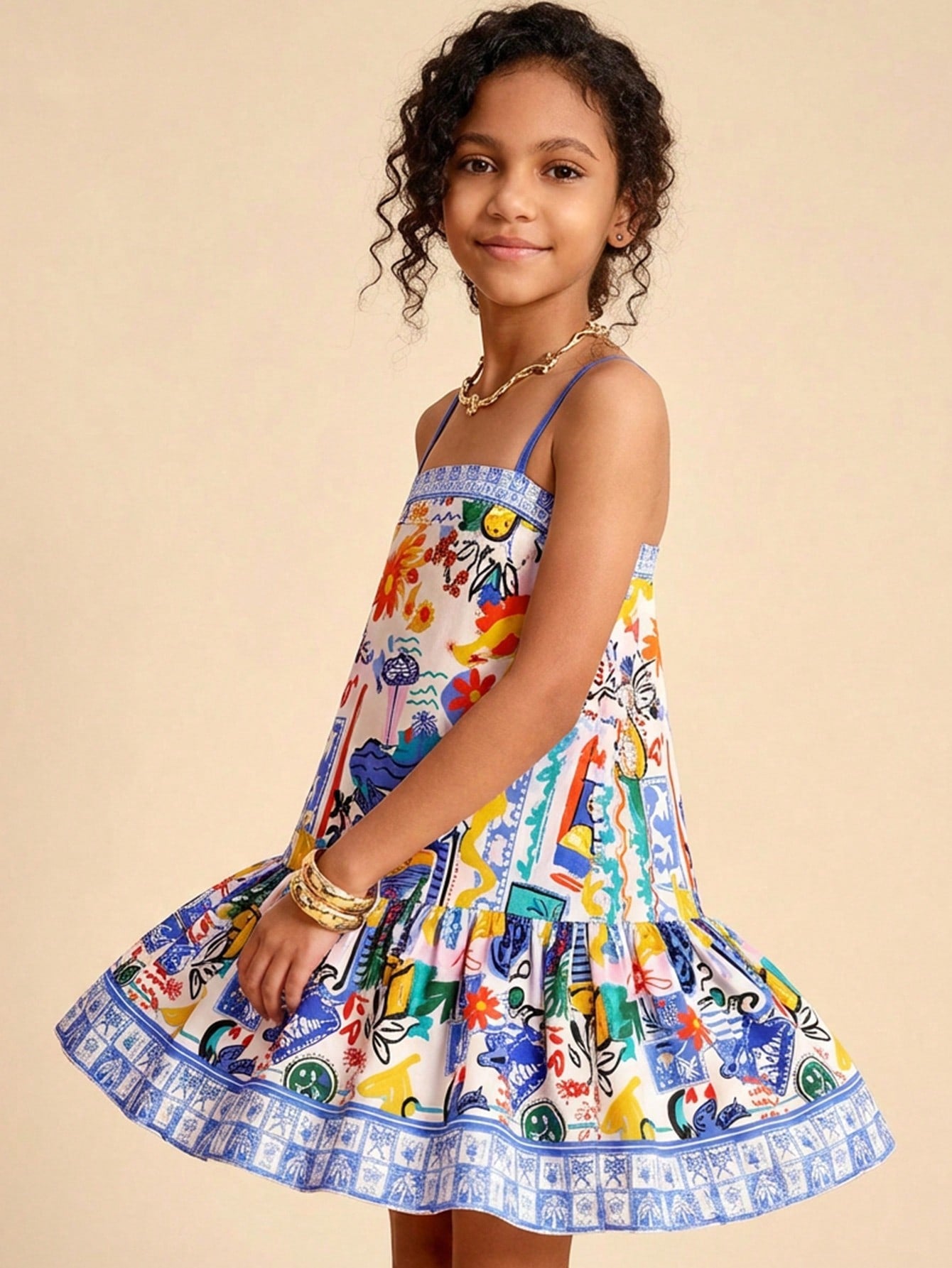 Tween girls black cami dress with colorful all-over cartoon print, spaghetti straps, ruffle detail, low waist, and flounce hem