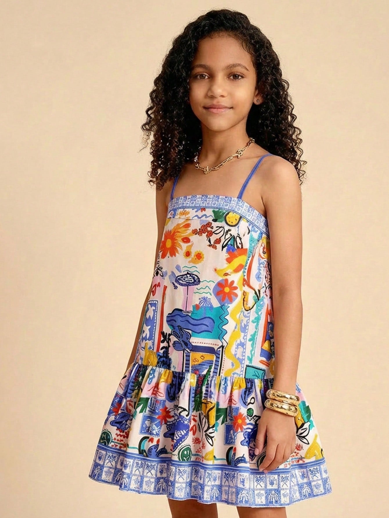 Tween girls black cami dress with colorful all-over cartoon print, spaghetti straps, ruffle detail, low waist, and flounce hem