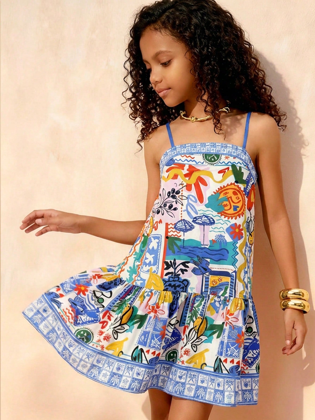 Tween girls black cami dress with colorful all-over cartoon print, spaghetti straps, ruffle detail, low waist, and flounce hem