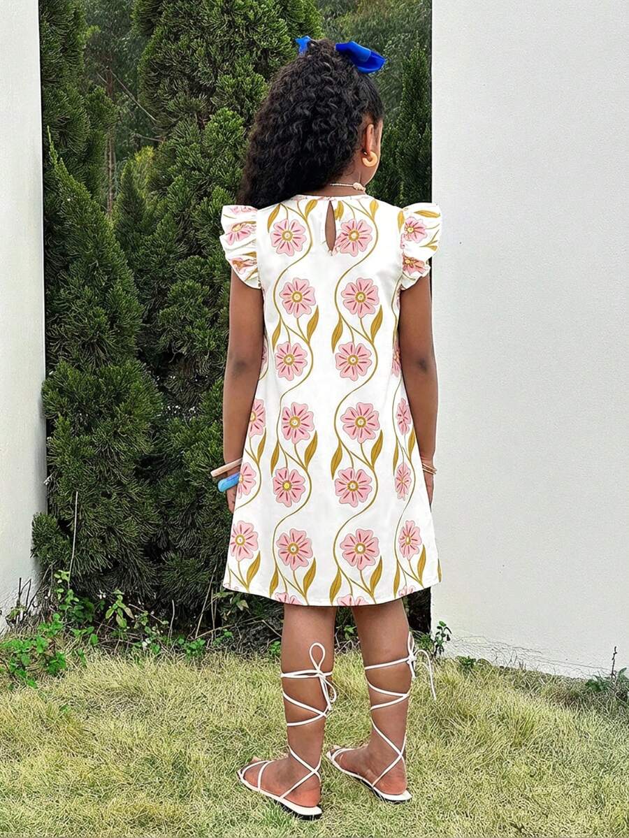 Tween girl wearing a blue ditsy floral patchwork tunic dress with ruffle button details and a round neckline.