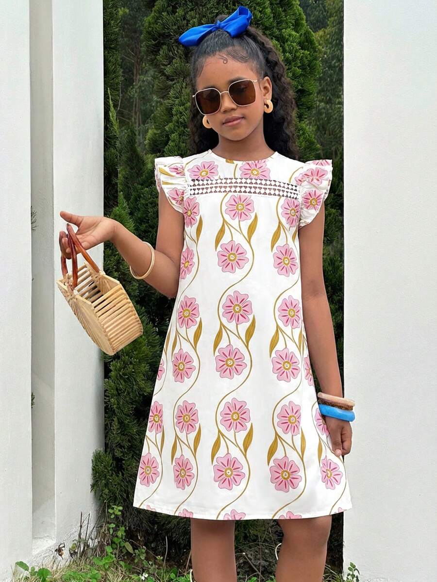 Tween girl wearing a blue ditsy floral patchwork tunic dress with ruffle button details and a round neckline.