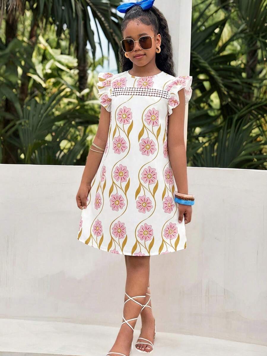Tween girl wearing a blue ditsy floral patchwork tunic dress with ruffle button details and a round neckline.