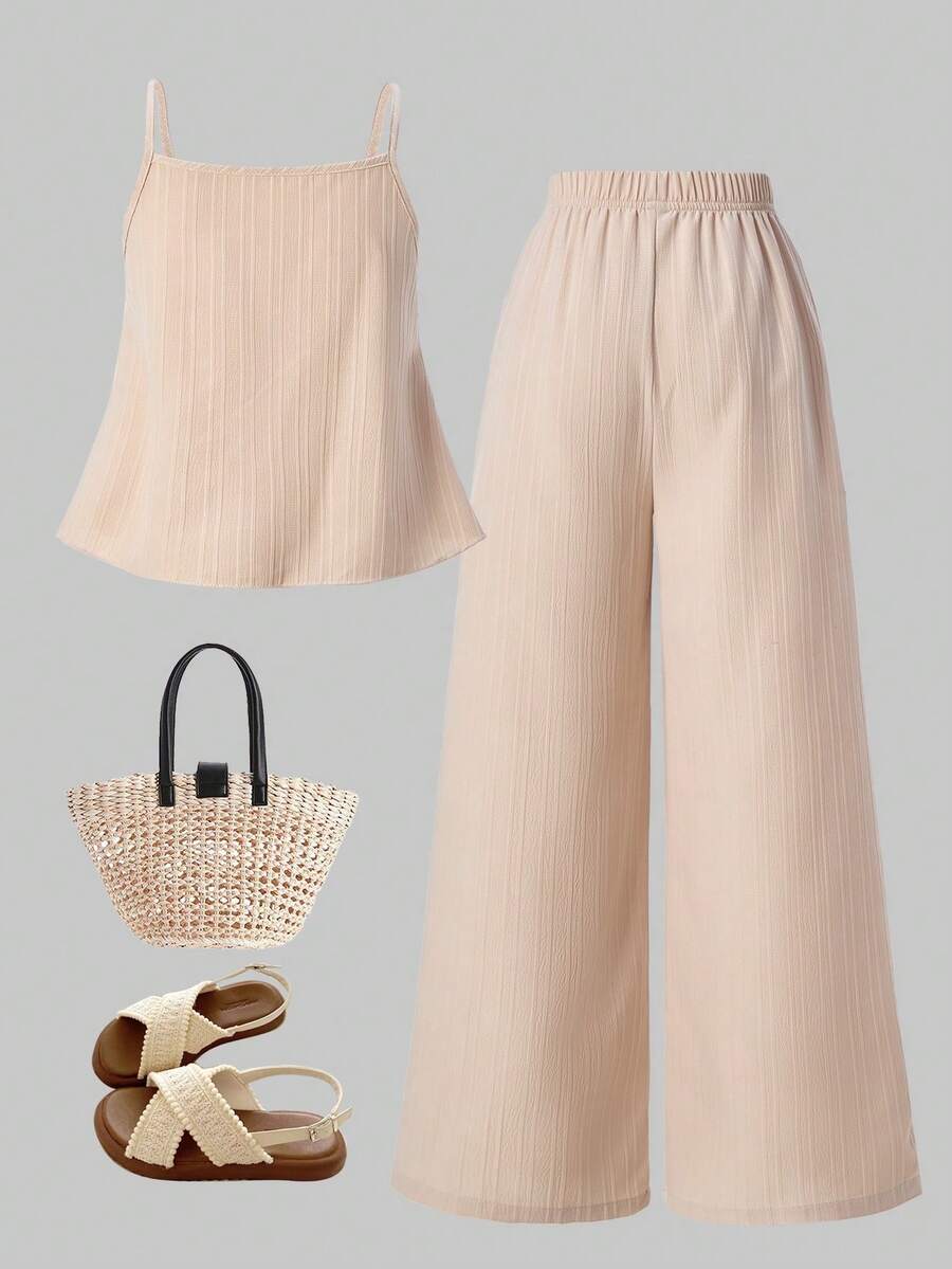 Tween girl wearing an apricot 2-piece outfit set featuring a shirred spaghetti strap short cami top and matching wide-leg long pants.
