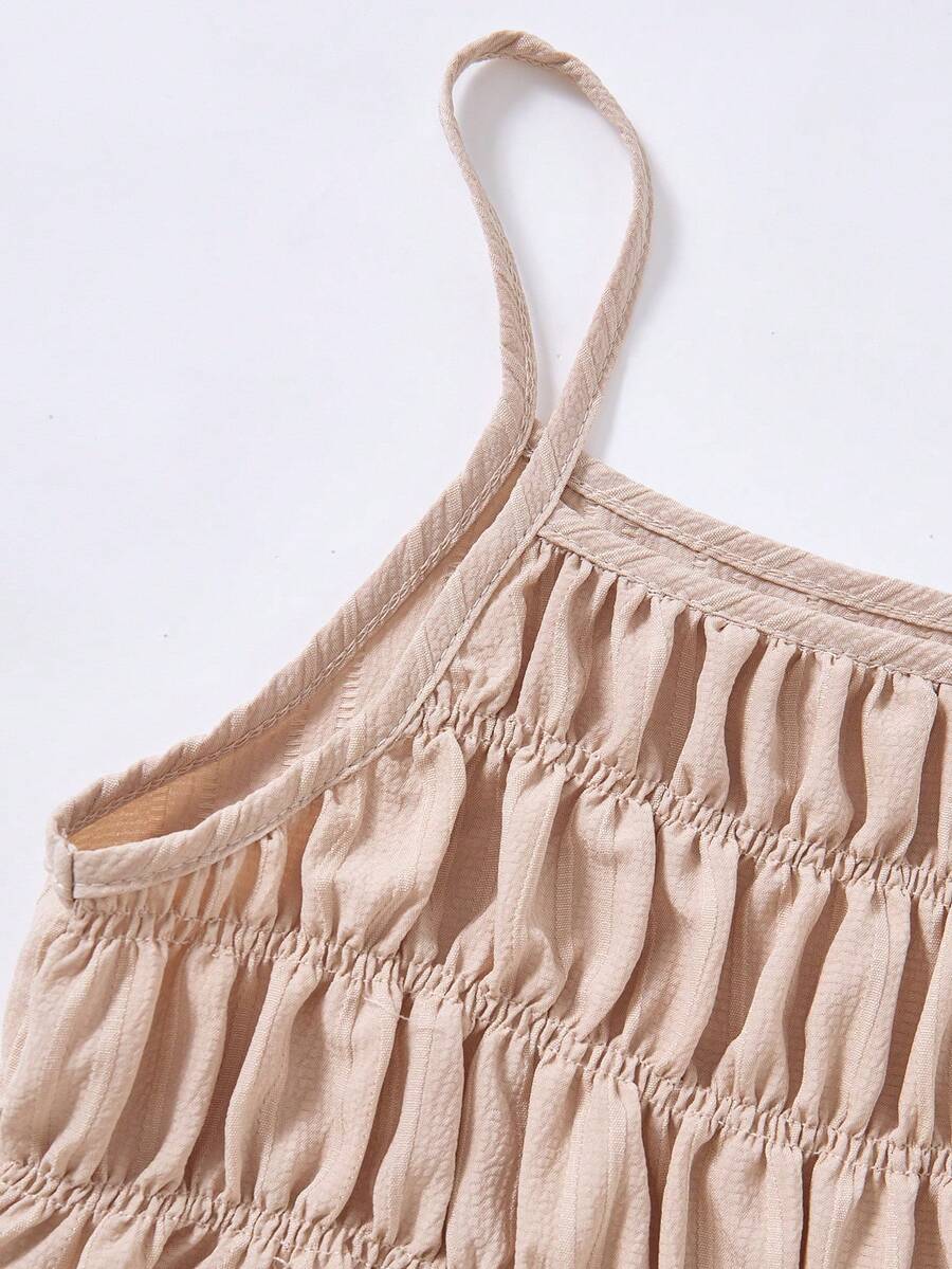 Tween girl wearing an apricot 2-piece outfit set featuring a shirred spaghetti strap short cami top and matching wide-leg long pants.