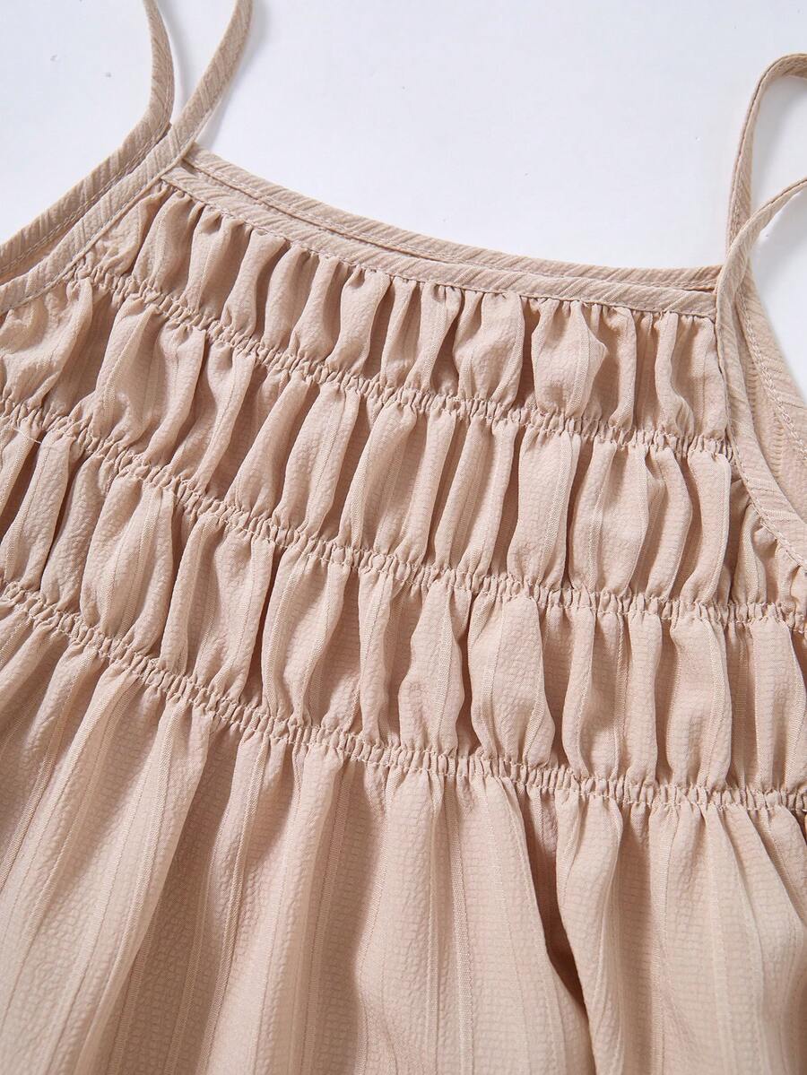 Tween girl wearing an apricot 2-piece outfit set featuring a shirred spaghetti strap short cami top and matching wide-leg long pants.