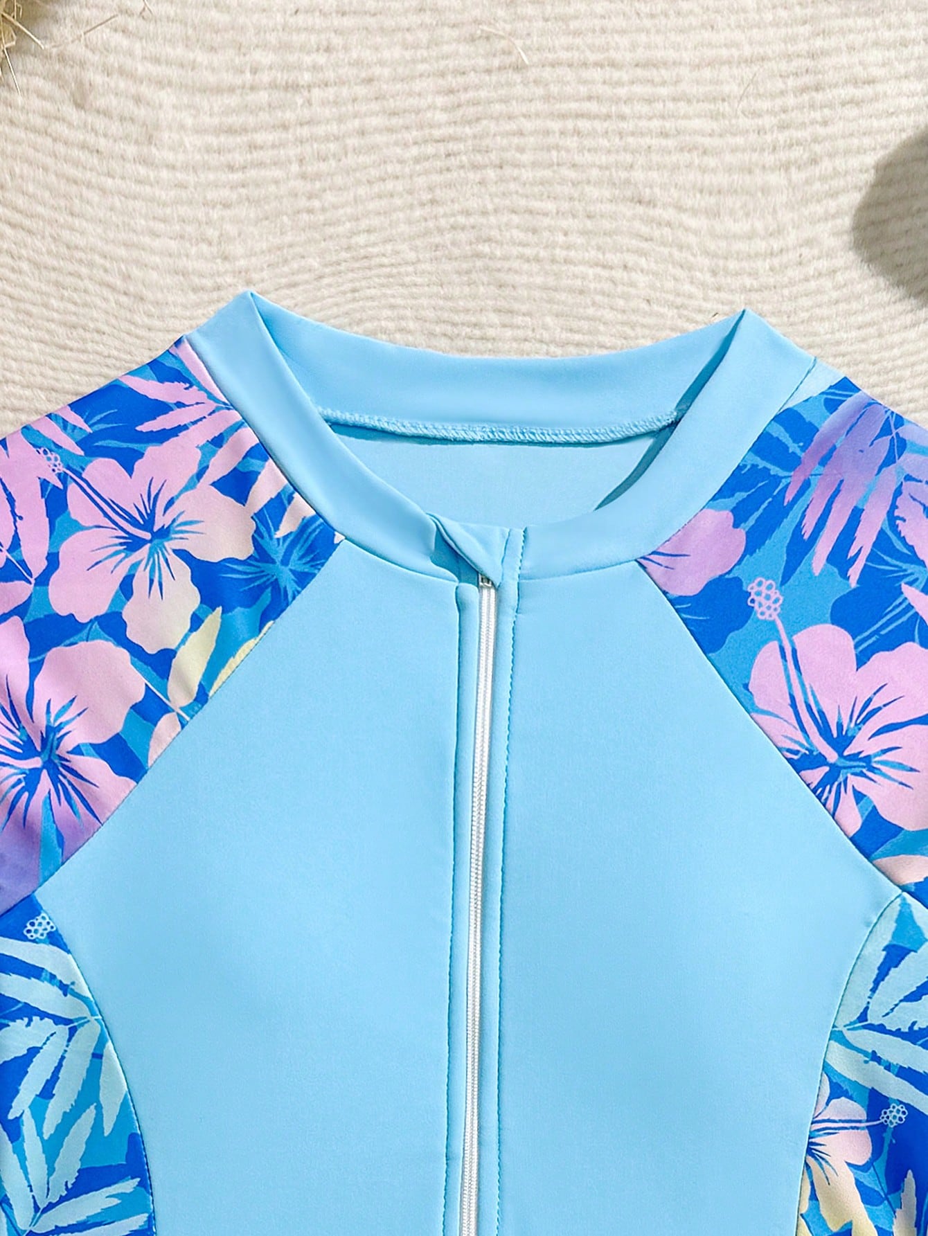 Tween girls one-piece swimsuit in black floral pattern with long sleeves, high neck, front zipper, and a skirt-style bottom.