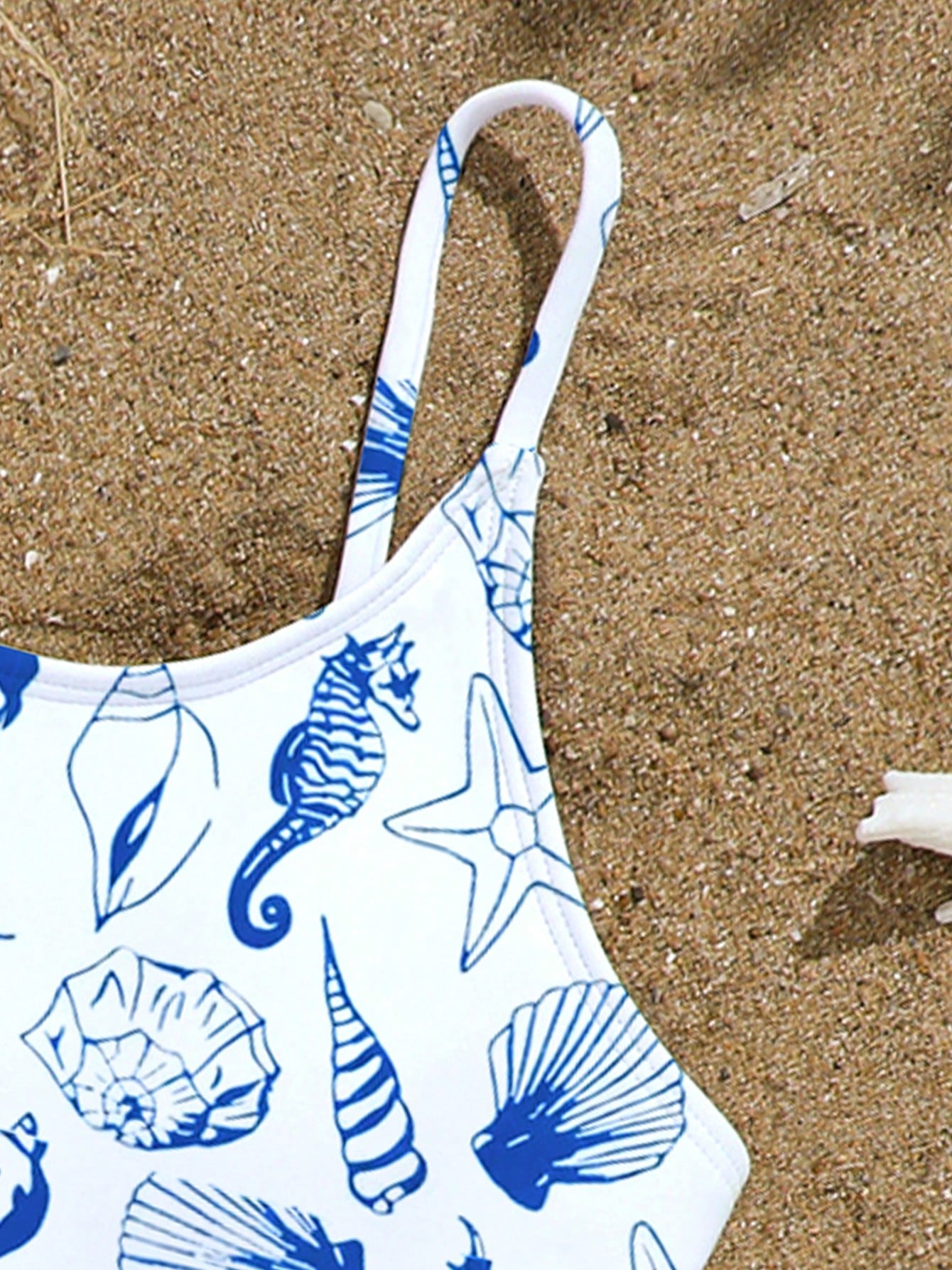 Tween girls one-piece swimsuit with multicolor ocean shell and seahorse all-over print, spaghetti straps, cut-out detail, and lined body for beach or swimming.