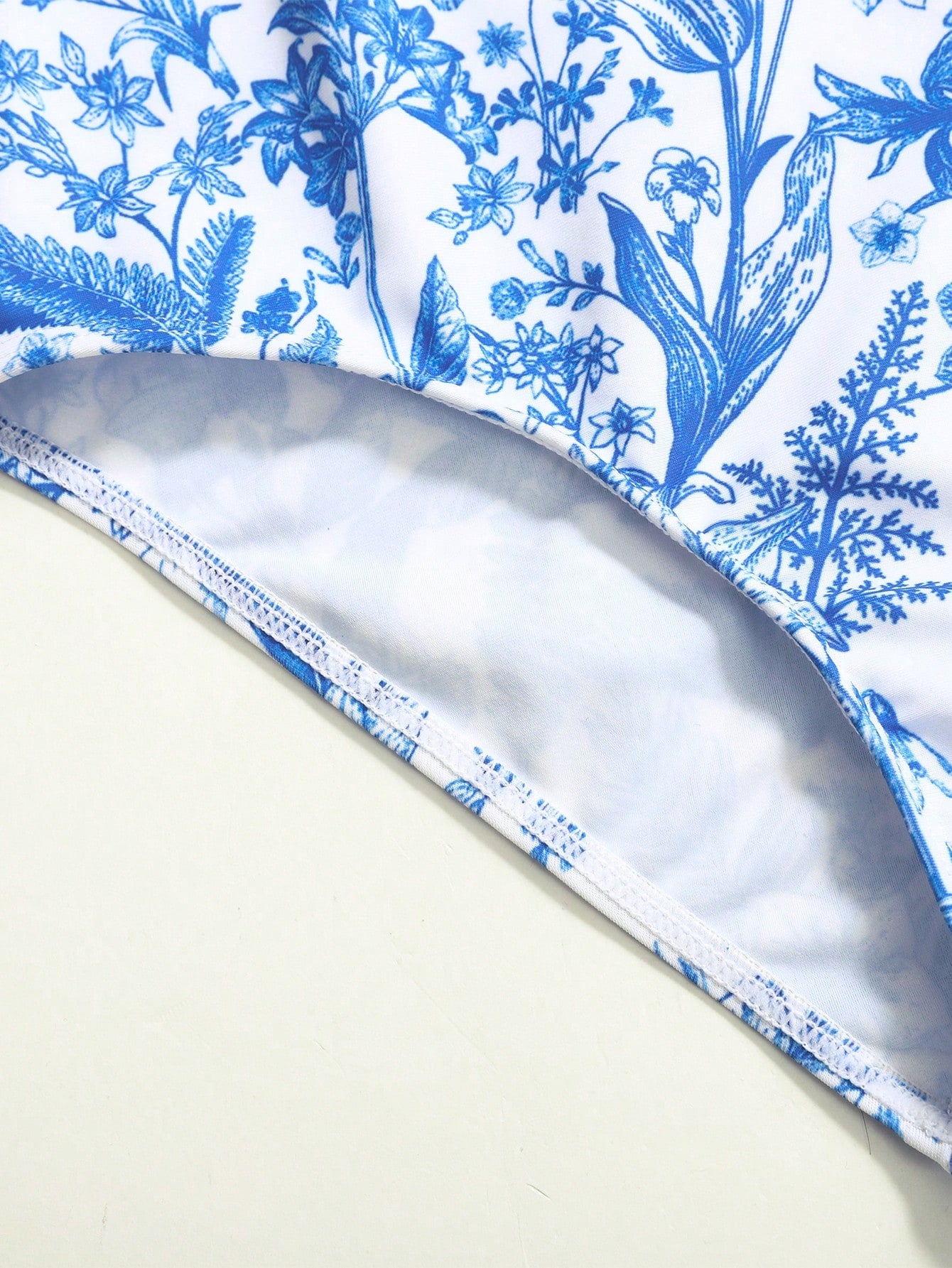 Tween girls blue and white floral print one-piece swimsuit with ruffle detail, spaghetti straps, V-neck styling, and vacation beachwear look.