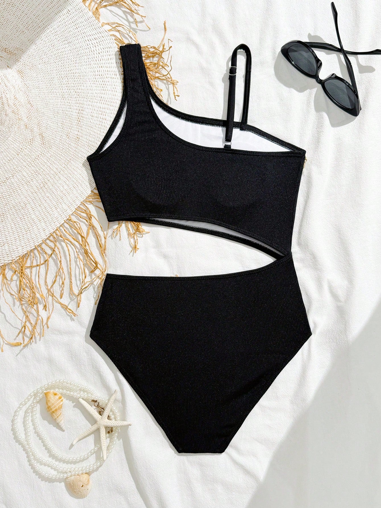 Girls black one-piece swimsuit with asymmetrical neckline, cutout waist detail, colorblock design, and medium-stretch swimsuit fabric for beach and pool wear.