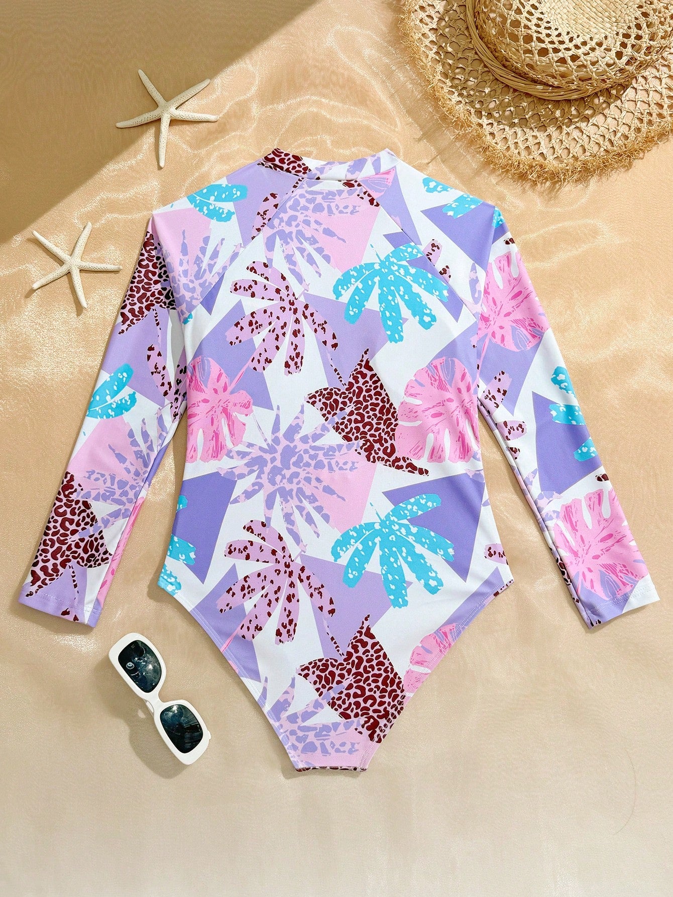 Girls one-piece swimsuit in blue with all-over leopard leaf print, ruffle detail, zipper front, high neck, and lined body for swimming and vacation.