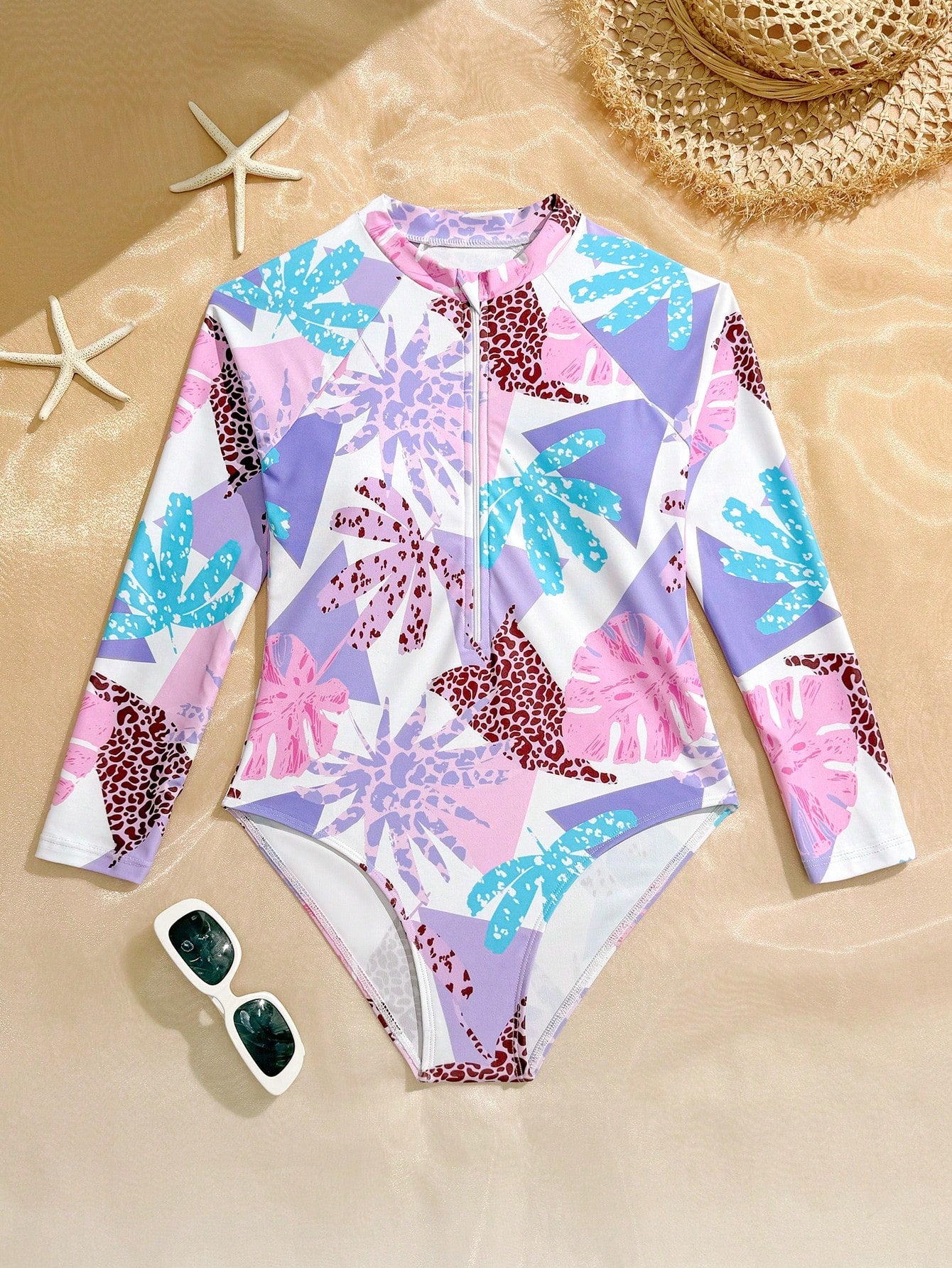 Girls one-piece swimsuit in blue with all-over leopard leaf print, ruffle detail, zipper front, high neck, and lined body for swimming and vacation.