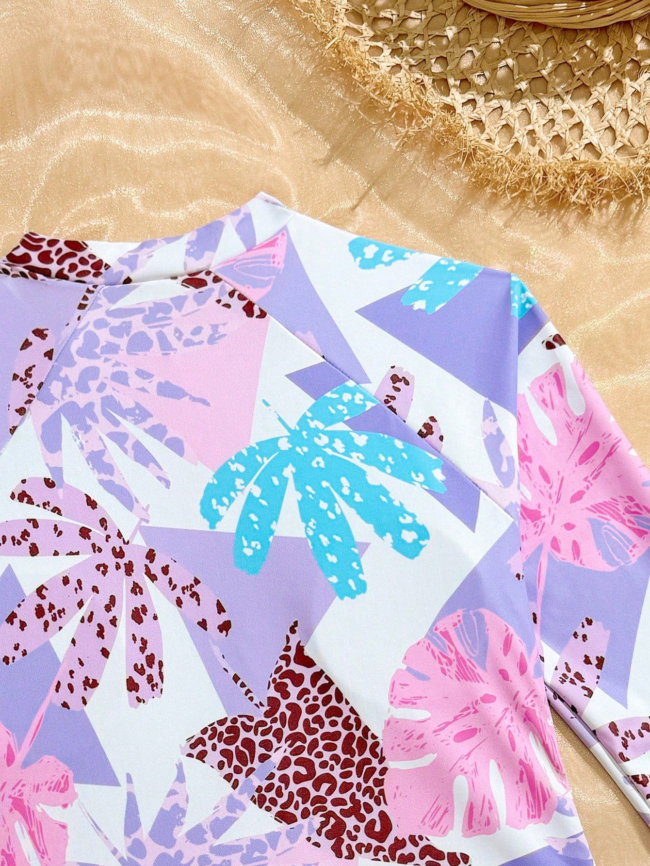 Girls one-piece swimsuit in blue with all-over leopard leaf print, ruffle detail, zipper front, high neck, and lined body for swimming and vacation.